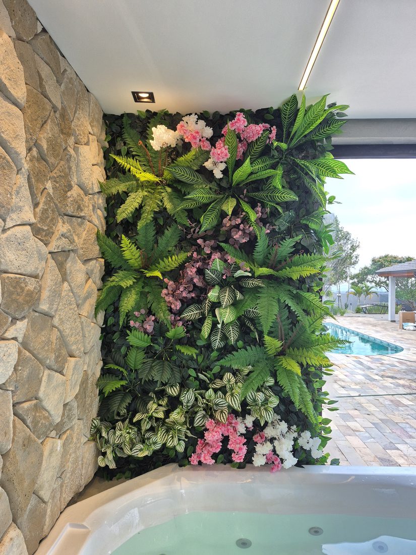 Parede de folhagem artificial com flores em área residencial