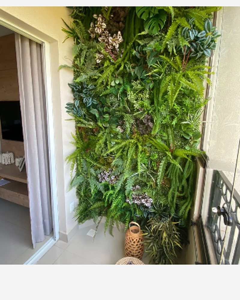 Jardim vertical de plantas artificiais na sacada de um apartamento