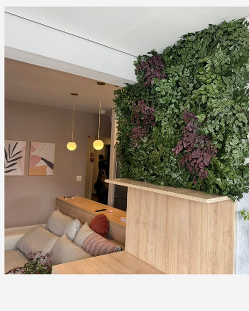 Jardim vertical de plantas artificiais na divisória da sala de estar